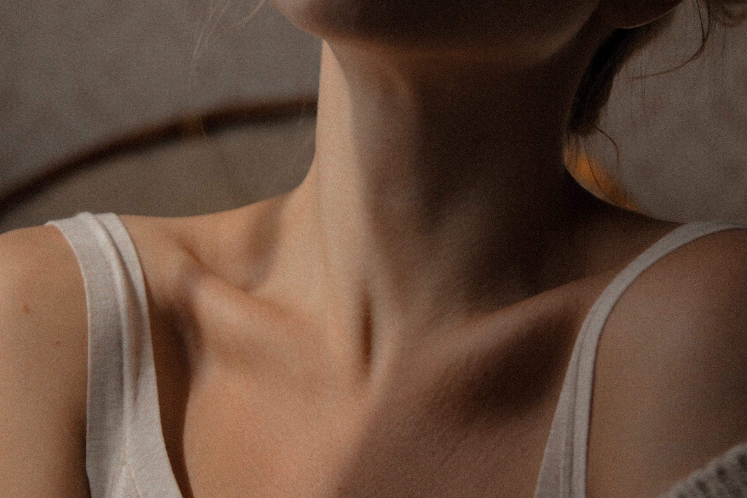 Woman wearing a white tank top exposing her collar bones and neck