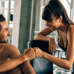 Two athletes at the gym smile and fist bump after a workout.